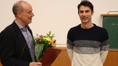 Der Dekan (links) überreicht den Lehrpreis der Fachschaft für das Sommersemester 2023an Jun.-Prof. Dr. Giancarlo Soavi.