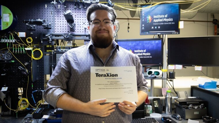 Georg R. Schwartz, PhD student at the research group Ultrafast Optics, proudly present his OPTICA Student Award at the lab in the IAP.