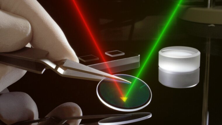 Artist's impression: Microscopic source for entangled photons. A laser (green) strikes a MoS2 crystal on a substrate. This emits long-wavelength photon pairs (red) which are entangled.