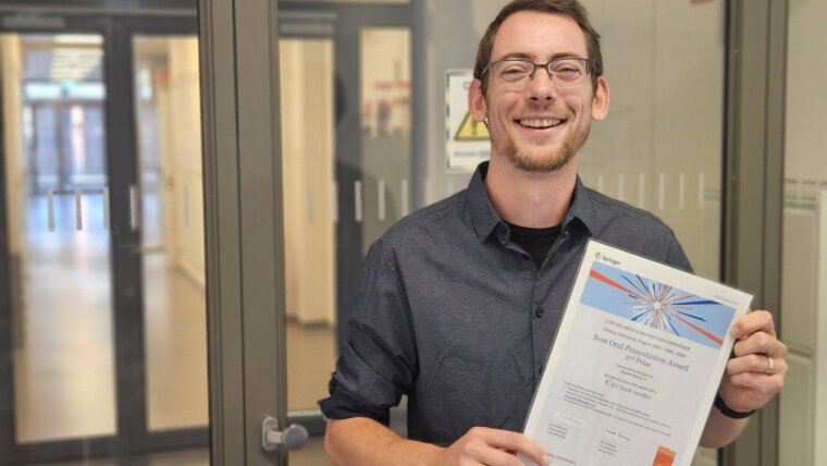 PhD student Mathias Lenski is delighted with his award in front of the laboratories in the ACP.